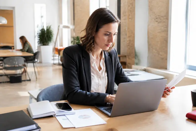 Un entrepreneur breton utilise son ordinateur portable dans un espace de coworking moderne à Rennes pour examiner ses documents financiers.