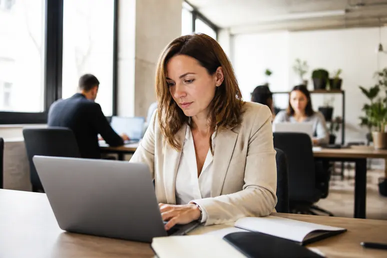 Entrepreneuse bretonne dans un espace de coworking, gérant ses finances professionnelles sur son ordinateur portable.