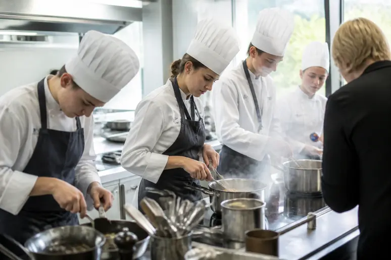 Apprentis cuisiniers en plein cours pratique à l'IFAC Brest, apprenant les techniques culinaires dans une cuisine professionnelle.