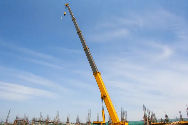 Segments télescopiques d'une flèche de grue en cours de déploiement hydraulique sur un chantier