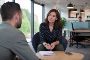 Une femme écoute attentivement un demandeur d'emploi pour devenir conseiller France Travail.