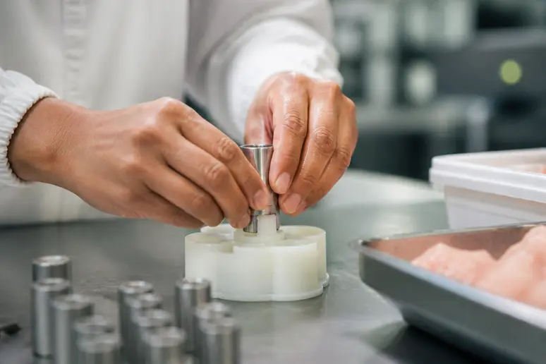 Des mains travaillant avec précision sur un assemblage technique dans un environnement professionnel propre.