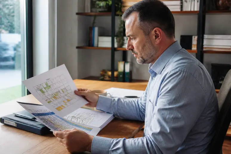 Un gestionnaire consulte un planning d'annualisation du temps de travail sur un bureau en bois.