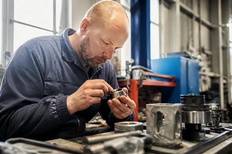 Technicien effectuant le contrôle d'une pièce mécanique dans un atelier de maintenance industrielle
